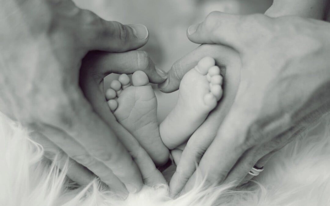 Pieds de bébé entourés par les mains des parents. La bulle parentale